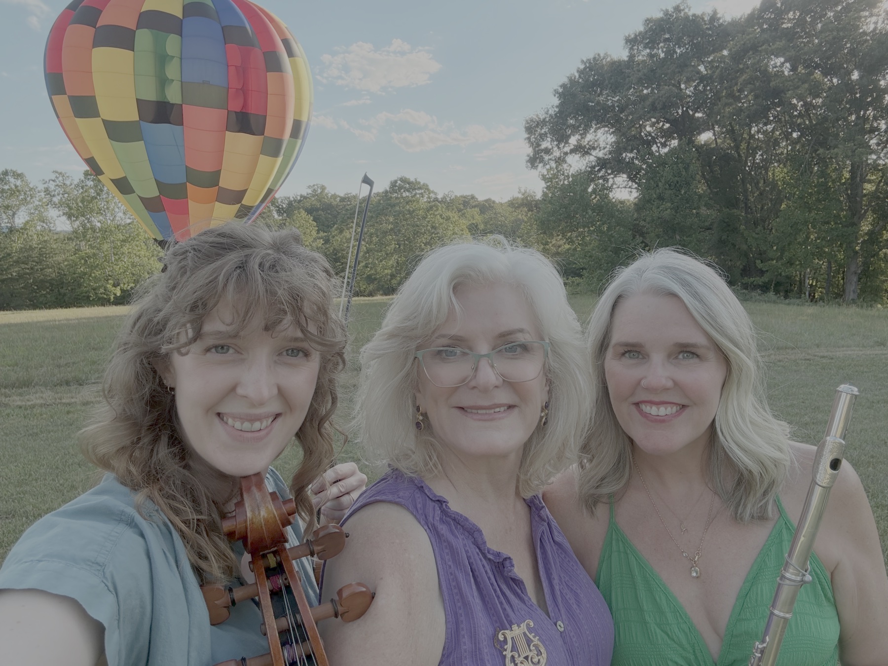 The Madison Trio, a flute, violin and cello trio, outdoors with a hot-air balloon